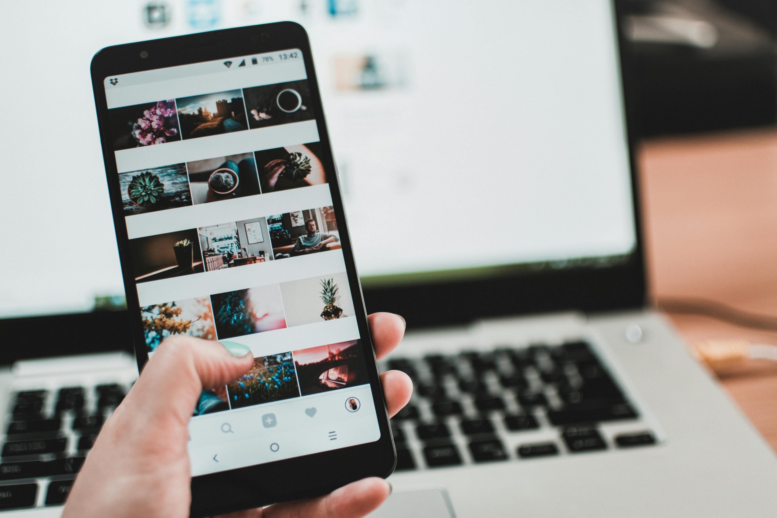 creative A person uses a smartphone to browse social media in front of a laptop, emphasizing modern technology and lifestyle.